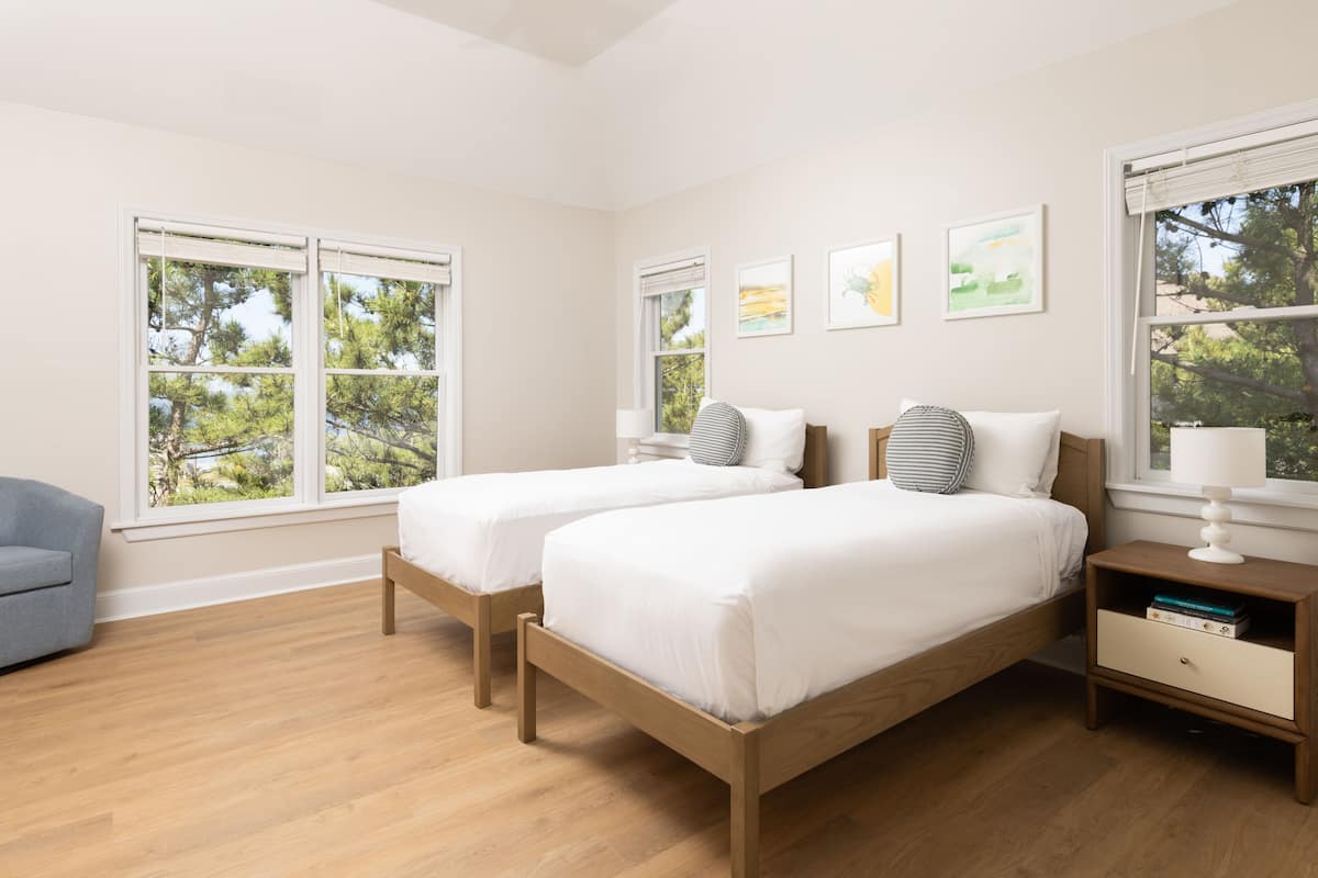 A bedroom with two beds, a nightstand, a lamp, and a chair.