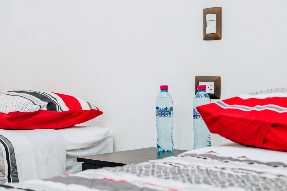 Habitación de hotel con una cama, almohadas, una mesa y dos botellas de agua.