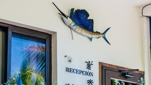 A reception area with a sign reading "RECEPCIÓN" and a decorative fish mounted on the wall.