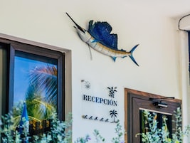 Uma área de recepção com uma placa indicando 'RECEPCIÓN' e um peixe decorativo pendurado na parede.