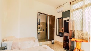 A hotel room with two beds, a bathroom with a shower, and a wooden side table.