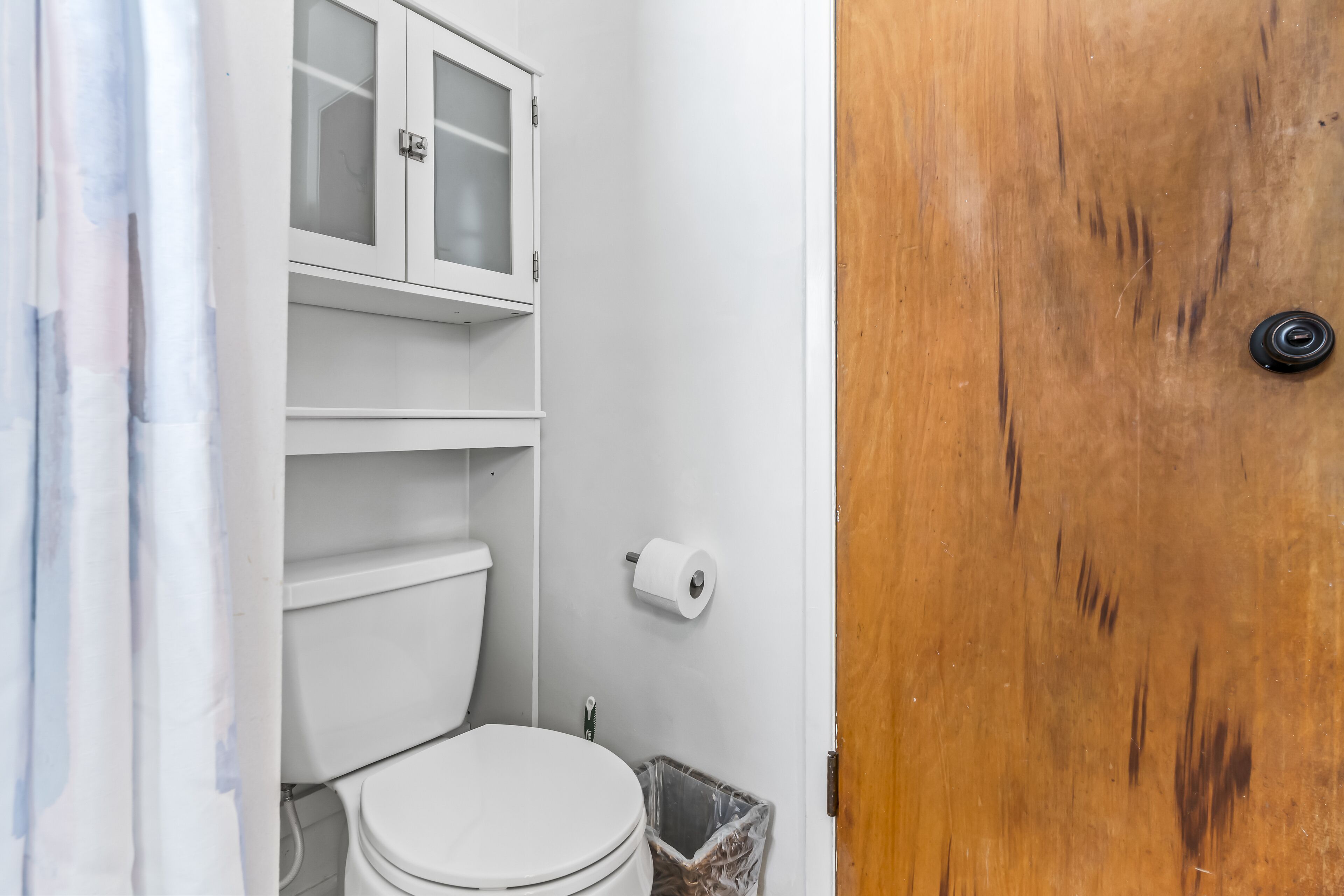 Ein Badezimmer mit Toilette, einem Schrank und einem Mülleimer.