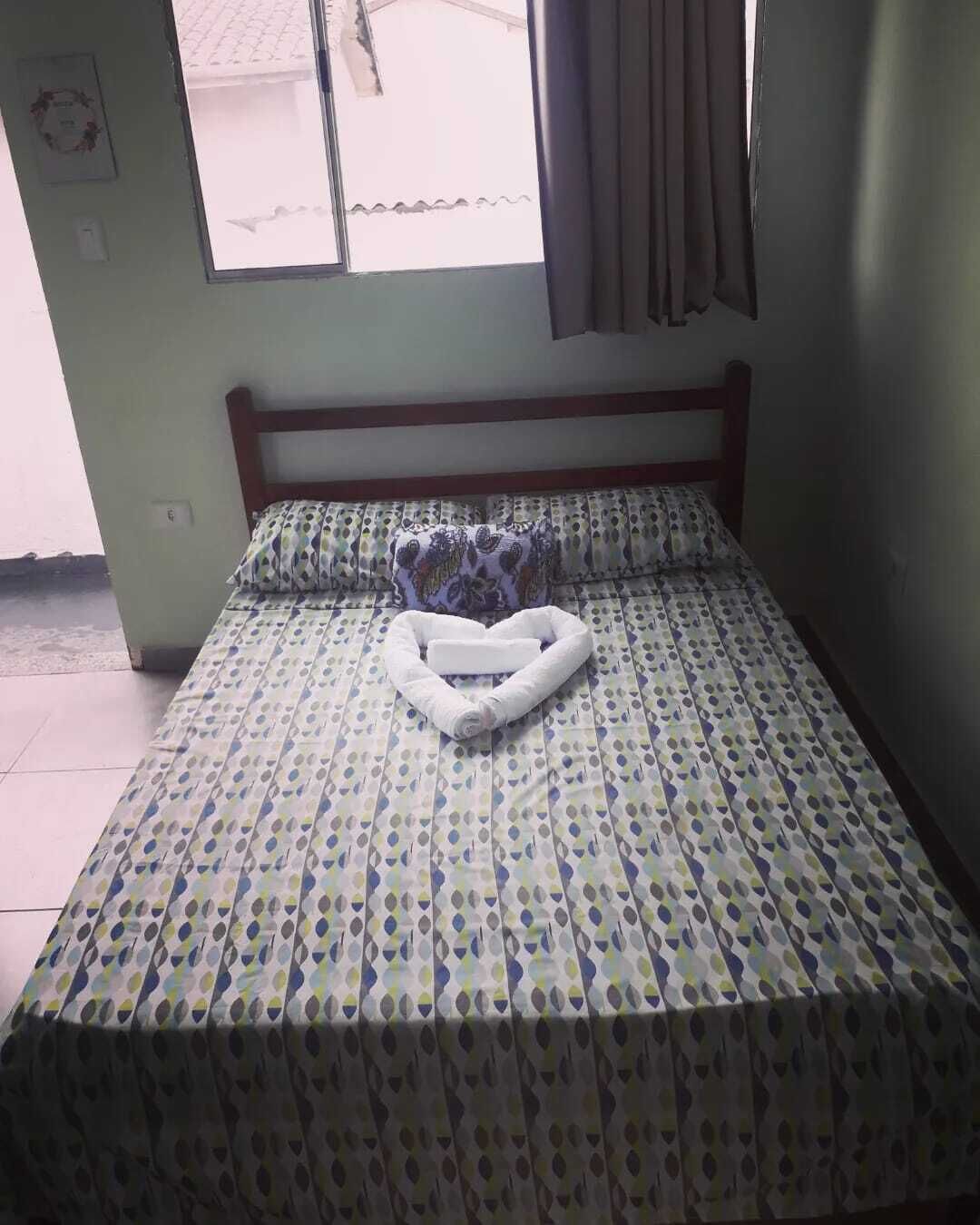 Una cama individual con un edredón estampado y un cojín con forma de corazón.