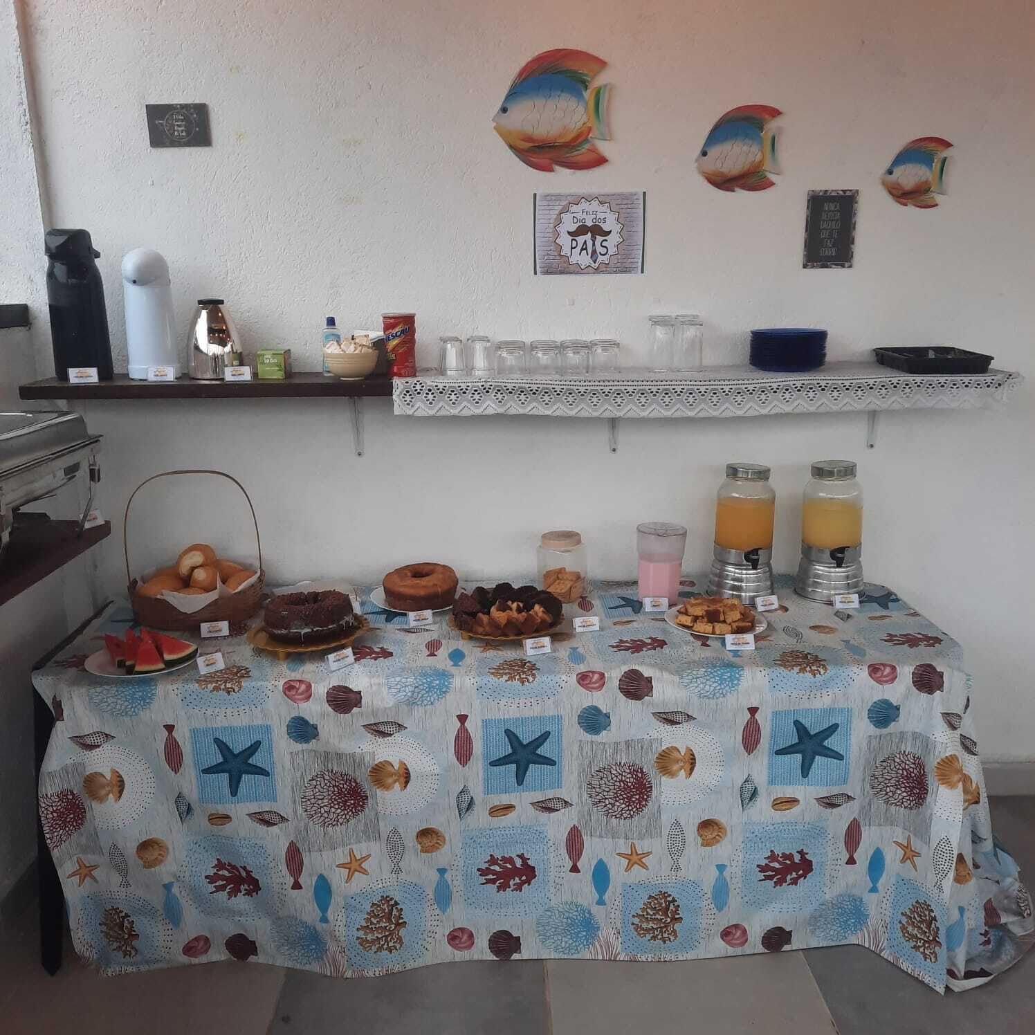 A breakfast buffet with various food items and beverages, a coffee machine, and decorative fish wall art.