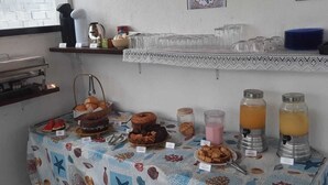 A breakfast buffet with various food items and drinks, a coffee machine, and decorative wall art. - Aguas Quentes (Caraguatatuba)
