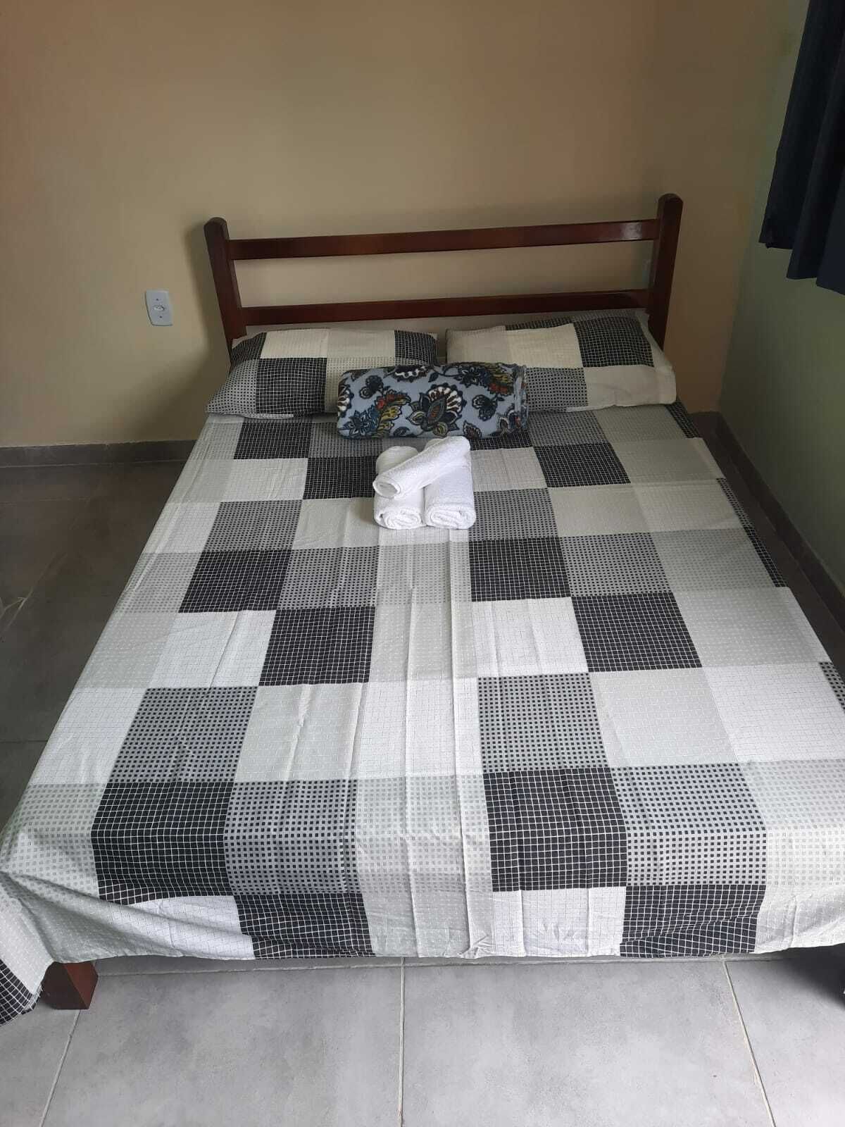 A bed with a checkered bedspread and two pillows, one with a floral pattern.