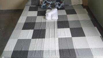 A bed with a checkered bedspread and two pillows, one with a floral pattern.