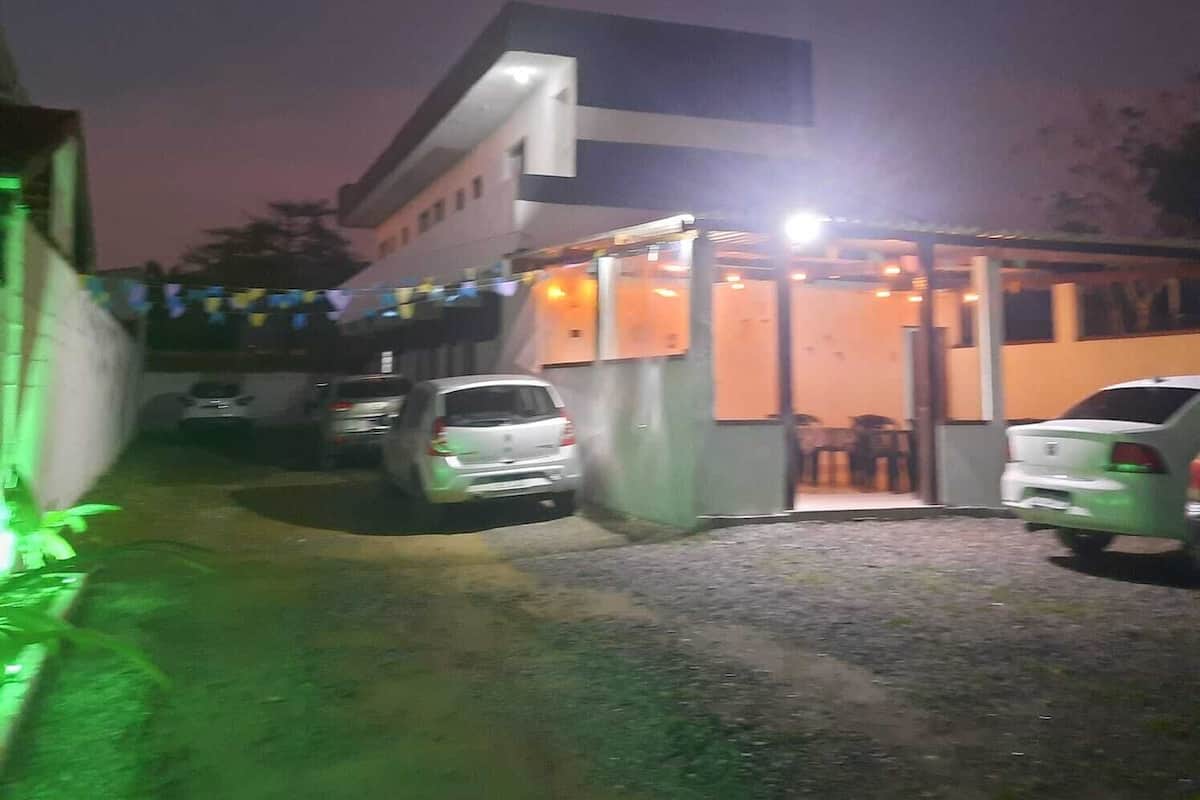 A building with a covered entrance and a parking area with several cars.