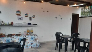 A dining area with a table and chairs, a buffet table with food and drinks, and a wall with decorative plates. - Aguas Quentes (Caraguatatuba)