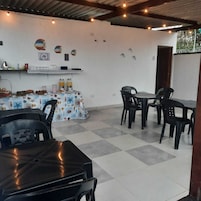 Un espace repas comprenant une table et des chaises, un buffet garni de plats et de boissons, et un mur décoré d’assiettes.