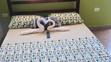 A bed with a patterned bedspread, pillows, and a heart-shaped pillow arrangement.