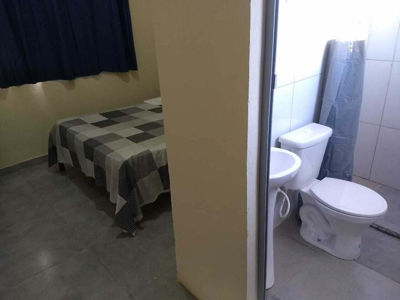 A small, compact room with a bed, a toilet, and a sink.