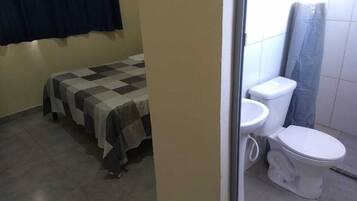 A small, compact room with a bed, a toilet, and a sink.