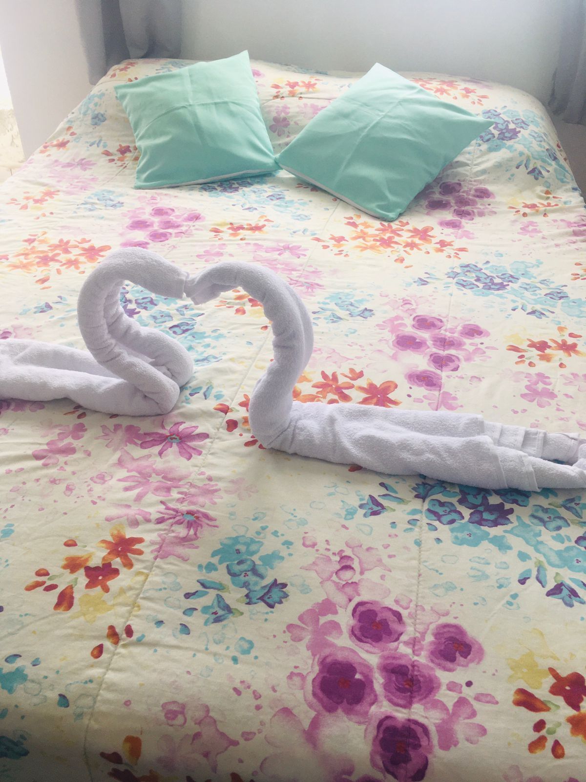 Uma cama com colcha florida e duas almofadas.