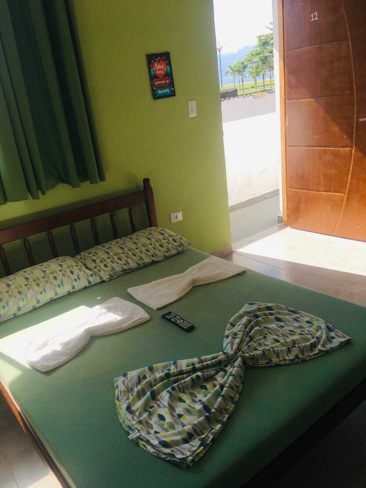 Une chambre avec un lit, un oreiller, une couverture et une télécommande.