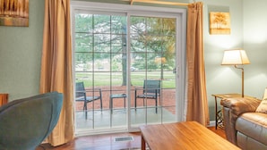 A room with a sliding glass door leading to an outdoor patio area with chairs and a table. - Townhouse in the Pines
 (Bloomington)