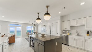 A modern kitchen with white cabinetry, a large island, and pendant lighting. - Villas at Sunset Beach  (Panama City Beach)