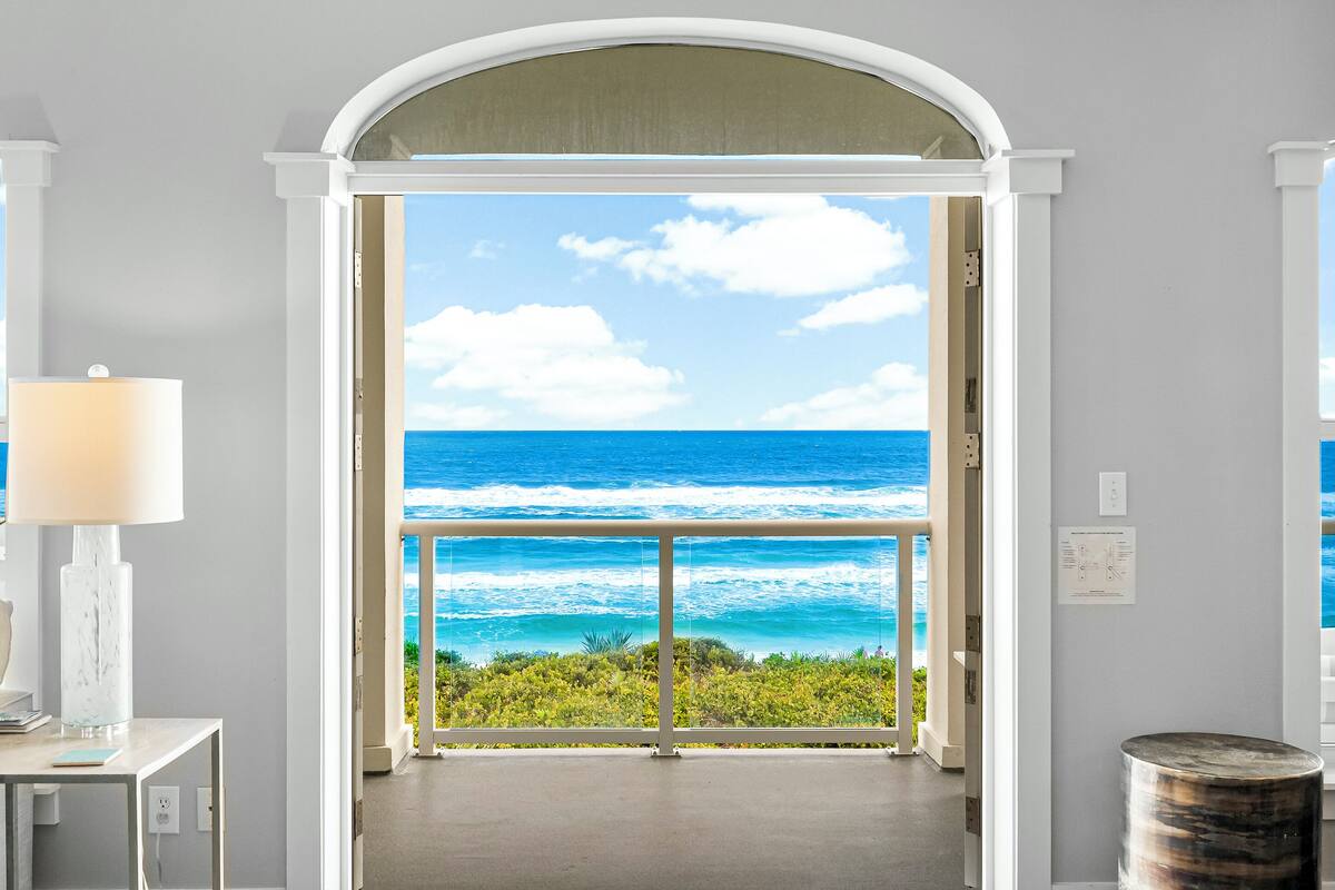 Een deuropening die uitkomt op een balkon met uitzicht op de oceaan.
