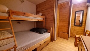 A bunk bed room with a wooden floor, a small table, and a mirror on the wall. - 20m from ski slopes, 2nd floor, view ski slopes, balcony, 48m², La Plagne (La Plagne)