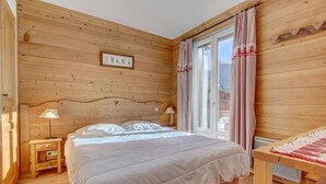A wooden-paneled bedroom with a bed, bedside lamps, and a window with curtains. - 2nd floor, balcony, parking, tv, ski locker, 45m², Morzine (Morzine)