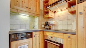 A compact kitchen with wooden cabinets, a built-in oven, and a coffee maker. - 2nd floor, balcony, parking, tv, ski locker, 45m², Morzine (Morzine)