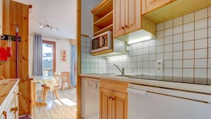 Een moderne keuken met houten kastjes, een magnetron en een betegelde spatwand.