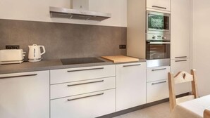 A modern kitchen with a built-in oven, a toaster, and a kettle on the countertop.