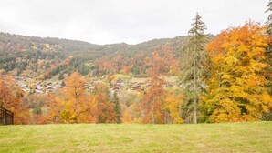 Een landelijk landschap met een dorpje verscholen tussen heuvels, met huizen in traditionele stijl en een helder uitzicht op de omliggende natuur.