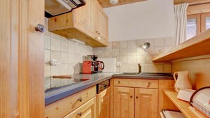A compact kitchen with wooden cabinets, a coffee maker, and a kettle on the counter. - Ground floor, balcony, parking, tv, ski locker, 68m², Morzine (Morzine)