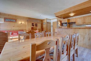 Een houten interieur met een eettafel, stoelen, houten kasten en een keukenhoek.