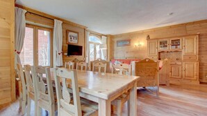 A wooden interior with a dining table and chairs, a television mounted on the wall, and a fireplace. - Ground floor, balcony, parking, tv, ski locker, 68m², Morzine (Morzine)