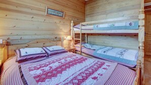 A wooden cabin bedroom with bunk beds, a wooden headboard, and a framed picture on the wall. - Ground floor, balcony, parking, tv, ski locker, 68m², Morzine (Morzine)