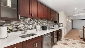 Una cocina moderna con armarios de madera oscura, salpicadero de azulejos, electrodomésticos de acero inoxidable y encimera blanca.