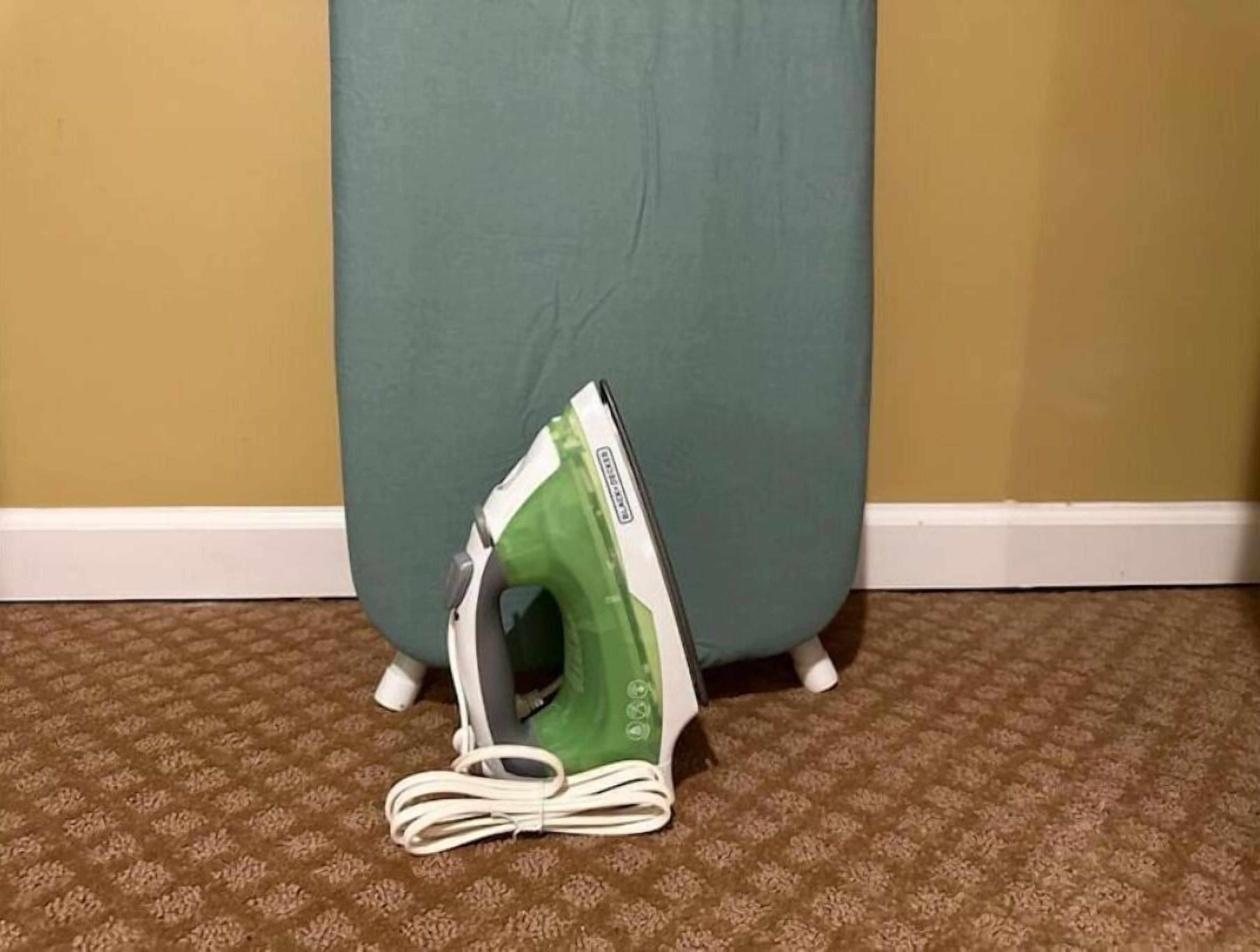 Una tabla de planchar verde con un cable blanco enrollado sobre una alfombra estampada.