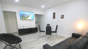 A modern living room with a flat-screen TV, a dining area with chairs, a sofa, and a lamp. - Diaz Stay Miami Airport (Miami)
