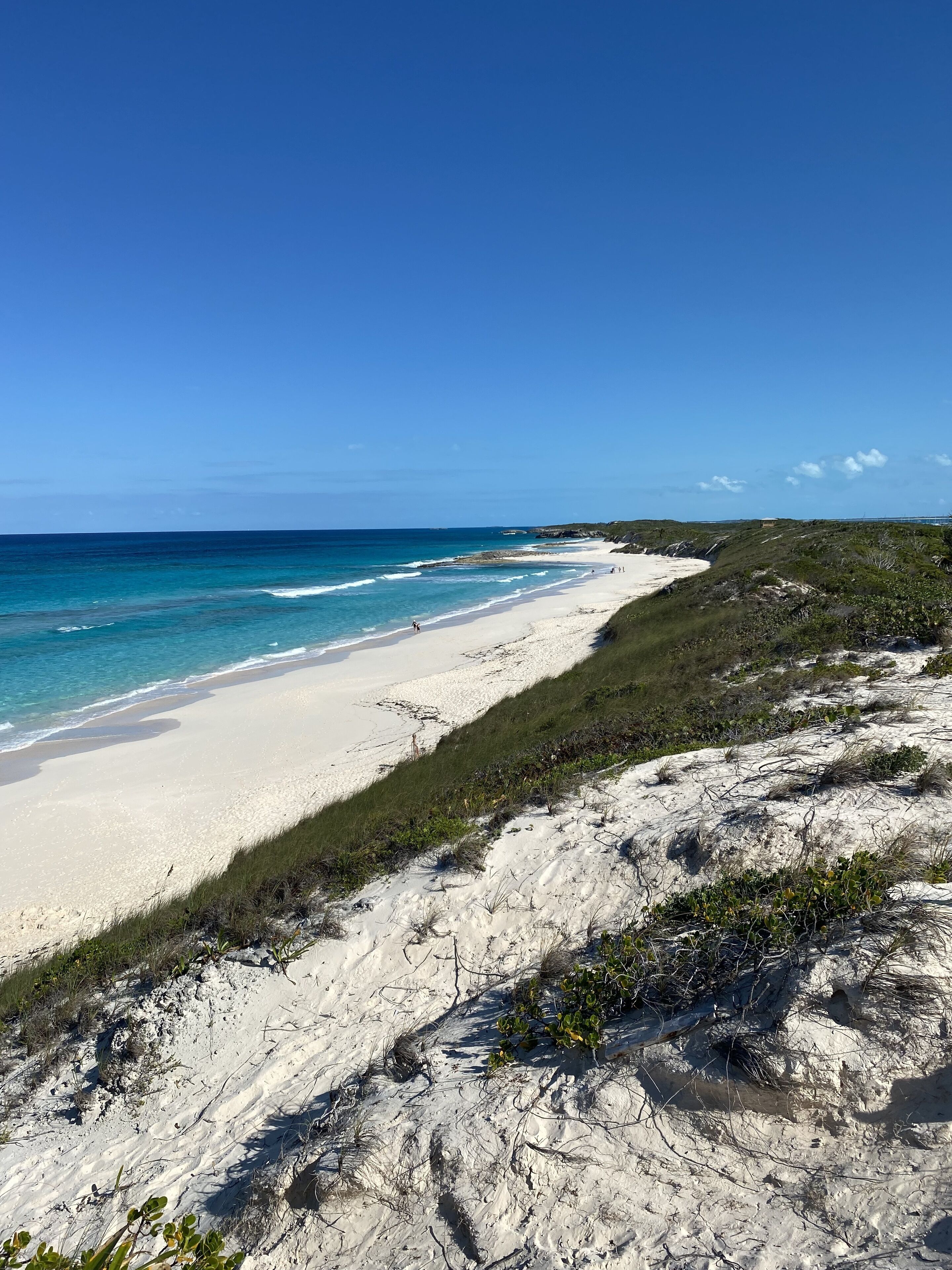 A beach with white sand and clear blue water.