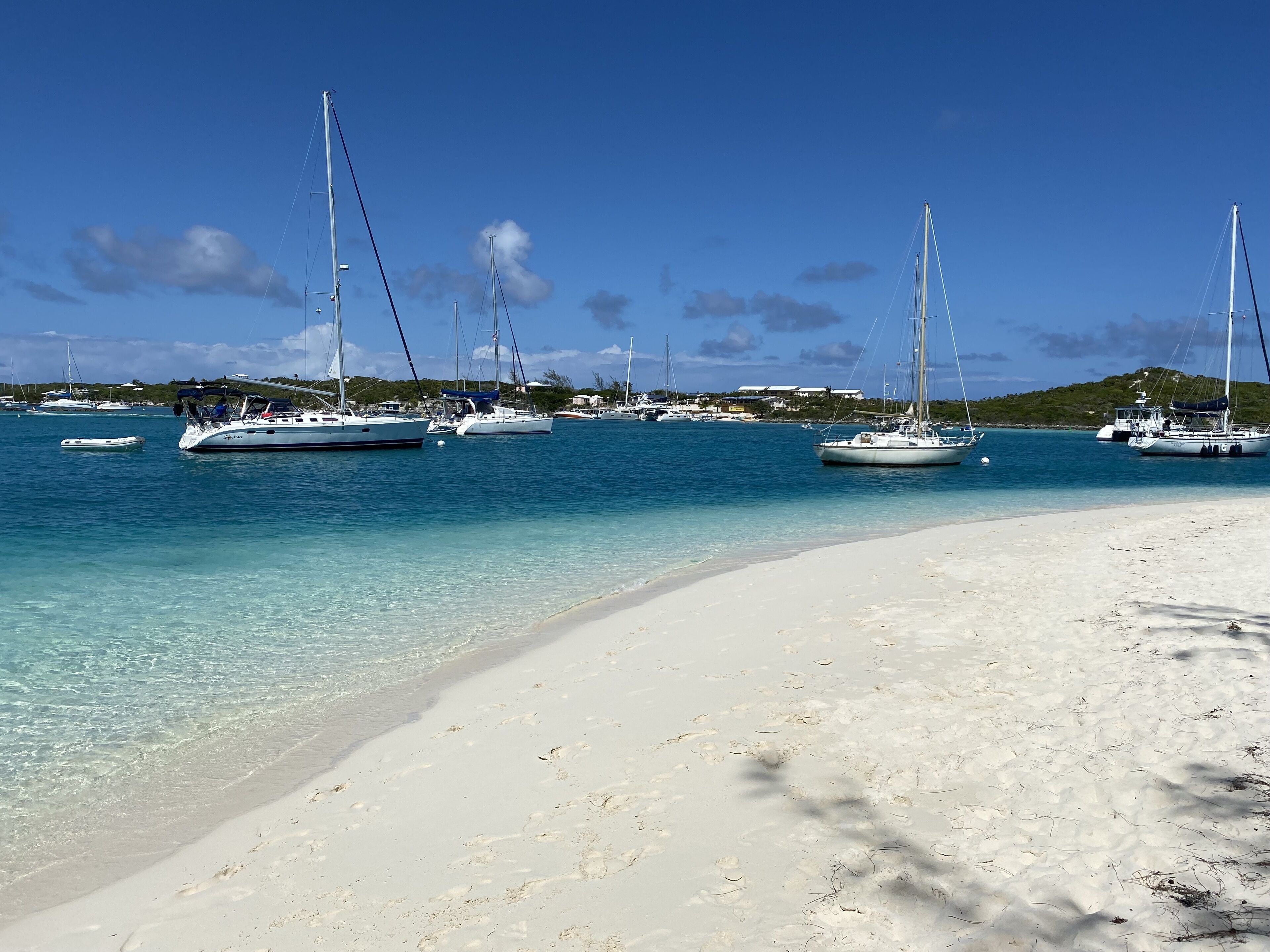 A beach with several sailboats anchored near the shore.