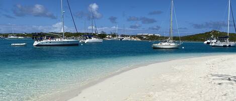 A beach with several sailboats anchored near the shore.