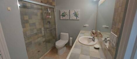 Ein Badezimmer mit einer Duschkabine, einer Toilette, einem Waschbecken und zwei an der Wand befestigten Schildkrötenbildern.