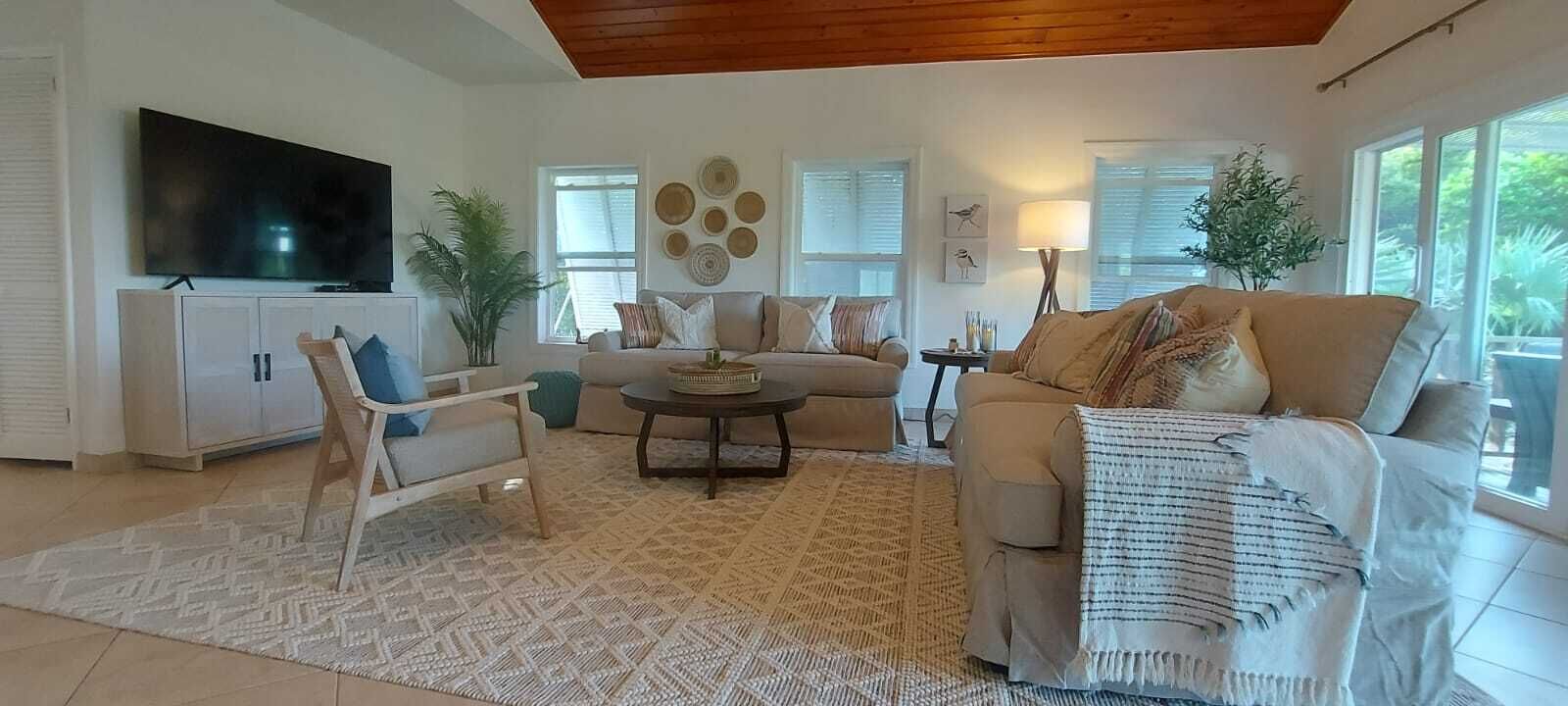 Un salon comprenant un canapé, un fauteuil, une table basse, un téléviseur et des objets de décoration.