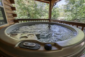 Ein Whirlpool mit Holzterrasse und Blick auf Bäume.