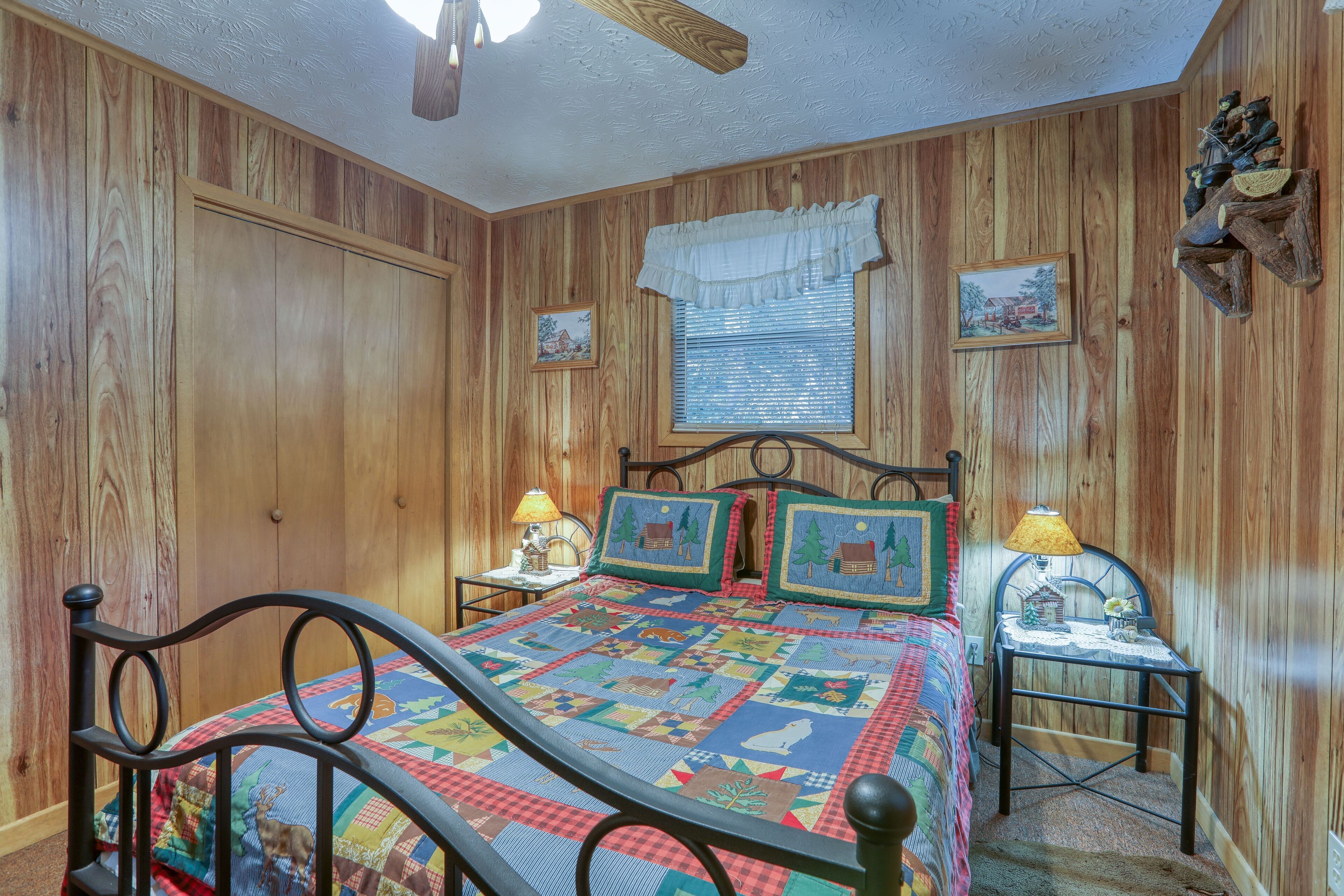 Ein Schlafzimmer mit Holzwänden, einem Bett, zwei Nachttischen, einem kleinen Tisch neben dem Bett und zwei gerahmten Bildern an der Wand.