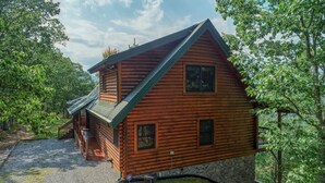 Une cabane en rondins avec des fondations en pierre, un toit en pente et une véranda.