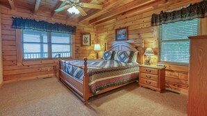Une chambre dans une cabane en bois, avec un lit, une commode et un ventilateur de plafond.
