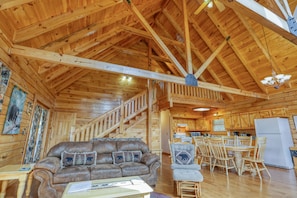 Interior de una cabaña de madera con sala de estar, comedor y cocina.