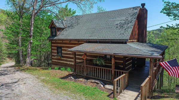 A rustic log cabin with a porch and a flag. - Bear Pause Cabin in the Smokies! (Sevierville)