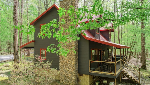 A cabin with a stone chimney, a balcony, and a staircase leading to a deck. - Elk Run is a stunning, two bedroom cabin situated directly on Cosby Creek. (Cosby)