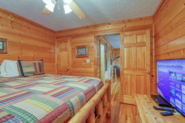 A wooden cabin bedroom with a bed, a television, and a wooden bench. - An Amazing View in Pigeon Forge. (Sevierville)