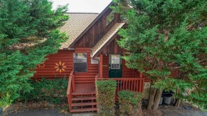 A rustic log cabin with a green door, a small porch, and a flower decoration on the wall. - An Amazing View in Pigeon Forge. (Sevierville)