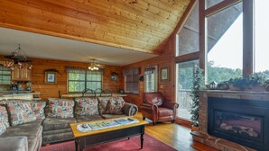 A cozy cabin interior with a wooden ceiling, a fireplace, a sofa set, and a dining area. - An Amazing View in Pigeon Forge. (Sevierville)